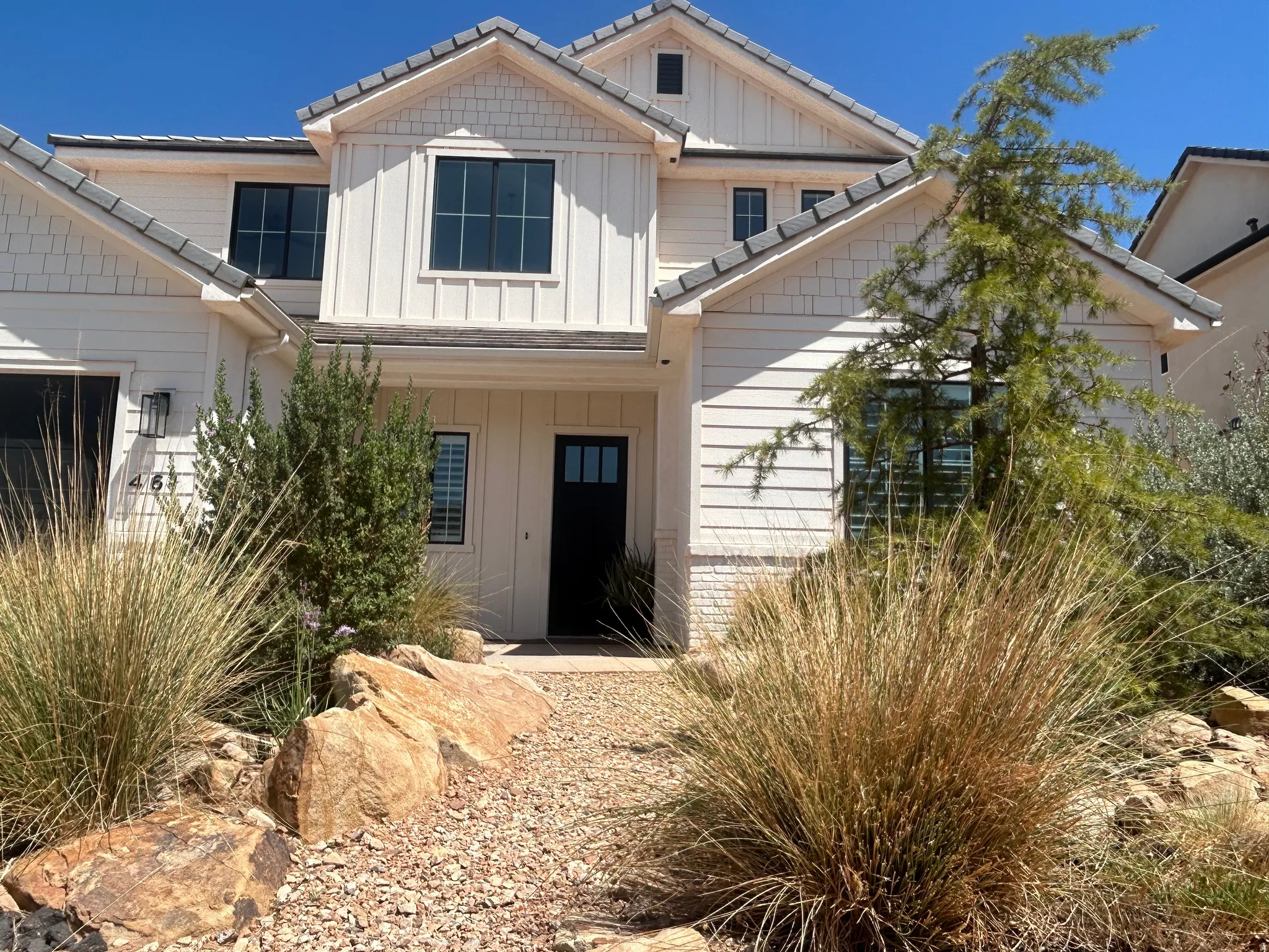 Contemporary two-story exterior featuring white horizontal siding, vertical board and batten accents, and shaker shingles