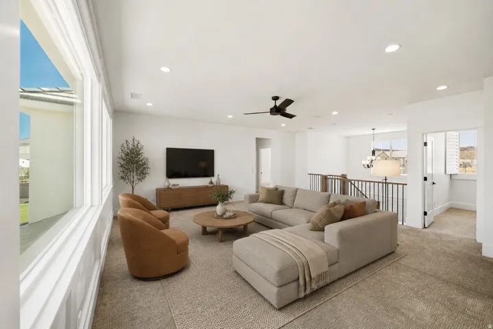 Spacious living area featuring a vaulted ceiling with recessed lighting and a ceiling fan, large windows, a built-in media console, and a carpeted floor
