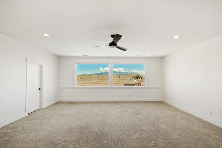 Spacious room featuring broad windows with mountain scenery, a ceiling fan, recessed lighting, and wall paneling