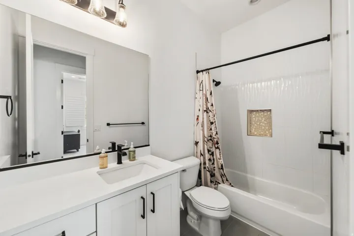 Bathroom featuring a white vanity with integrated sink, black fixtures, and a large mirror
