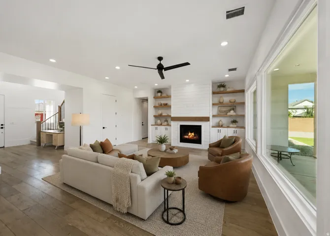 Spacious living area featuring wood-finish flooring, a shiplap fireplace with wood mantel, built-in shelving and cabinetry, and recessed lighting