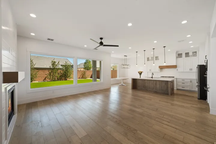 Open concept living area featuring wood-finish flooring, a linear fireplace with white shiplap surround, and a ceiling fan