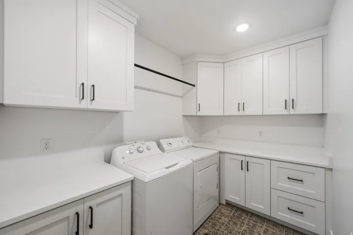 Laundry room featuring white shaker-style cabinetry, ample countertop space, and a built-in hanging rod