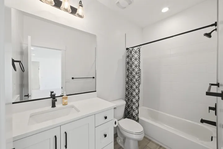 Bathroom featuring a white vanity with an integrated rectangular sink, a large wall-mounted mirror, and black hardware