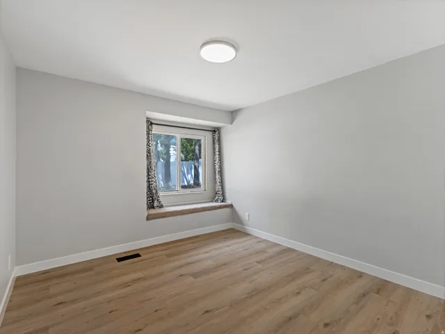 Neutral gray walls with white trim, wood-finish flooring, and a built-in window seat
