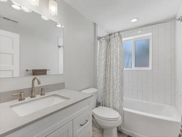 Bathroom featuring a white vanity with an integrated sink, brushed nickel faucet, and a large mirror