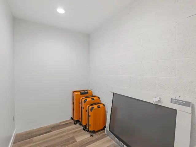 Compact storage area featuring wood-finish flooring, white painted walls, and a recessed ceiling light