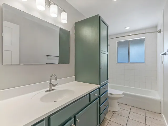 Bathroom featuring a single-sink vanity with white countertop, chrome faucet, and teal cabinetry