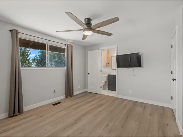 Spacious room featuring wood-finish flooring, a contemporary ceiling fan with integrated lighting, and a large window