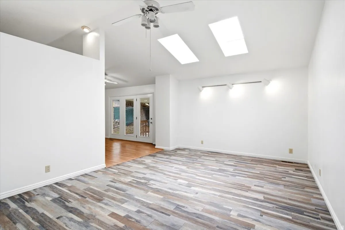 Spacious interior featuring wood-finish flooring, high ceilings, multiple skylights, and track lighting