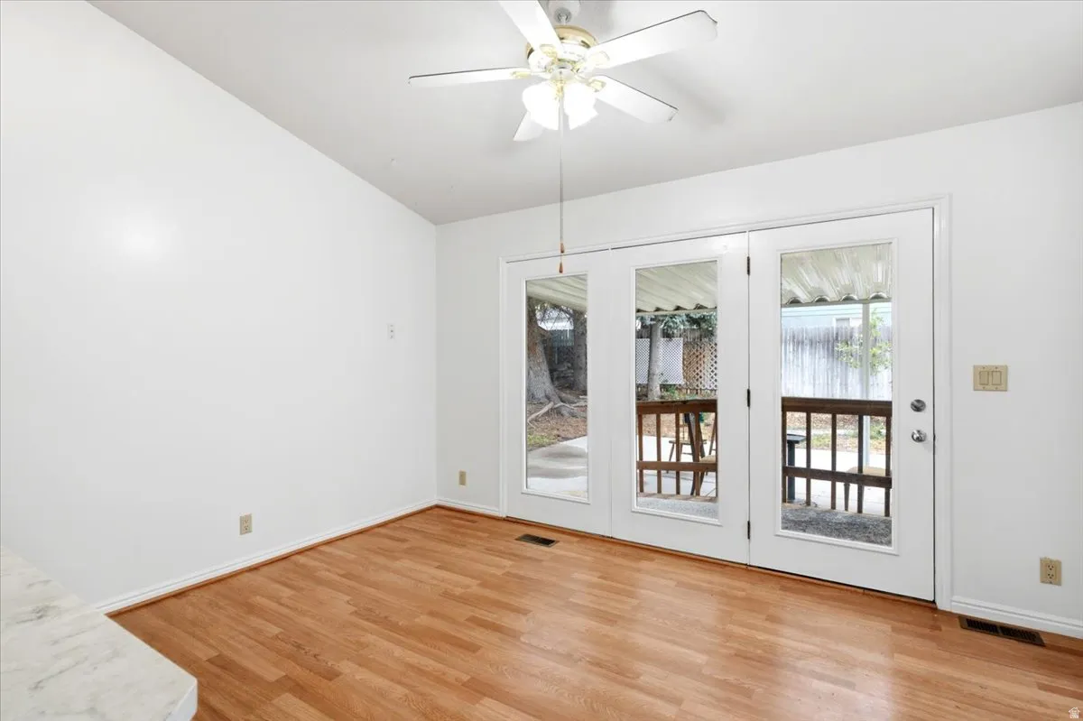 Room featuring wood-finish flooring, a ceiling fan with integrated lighting, and white walls