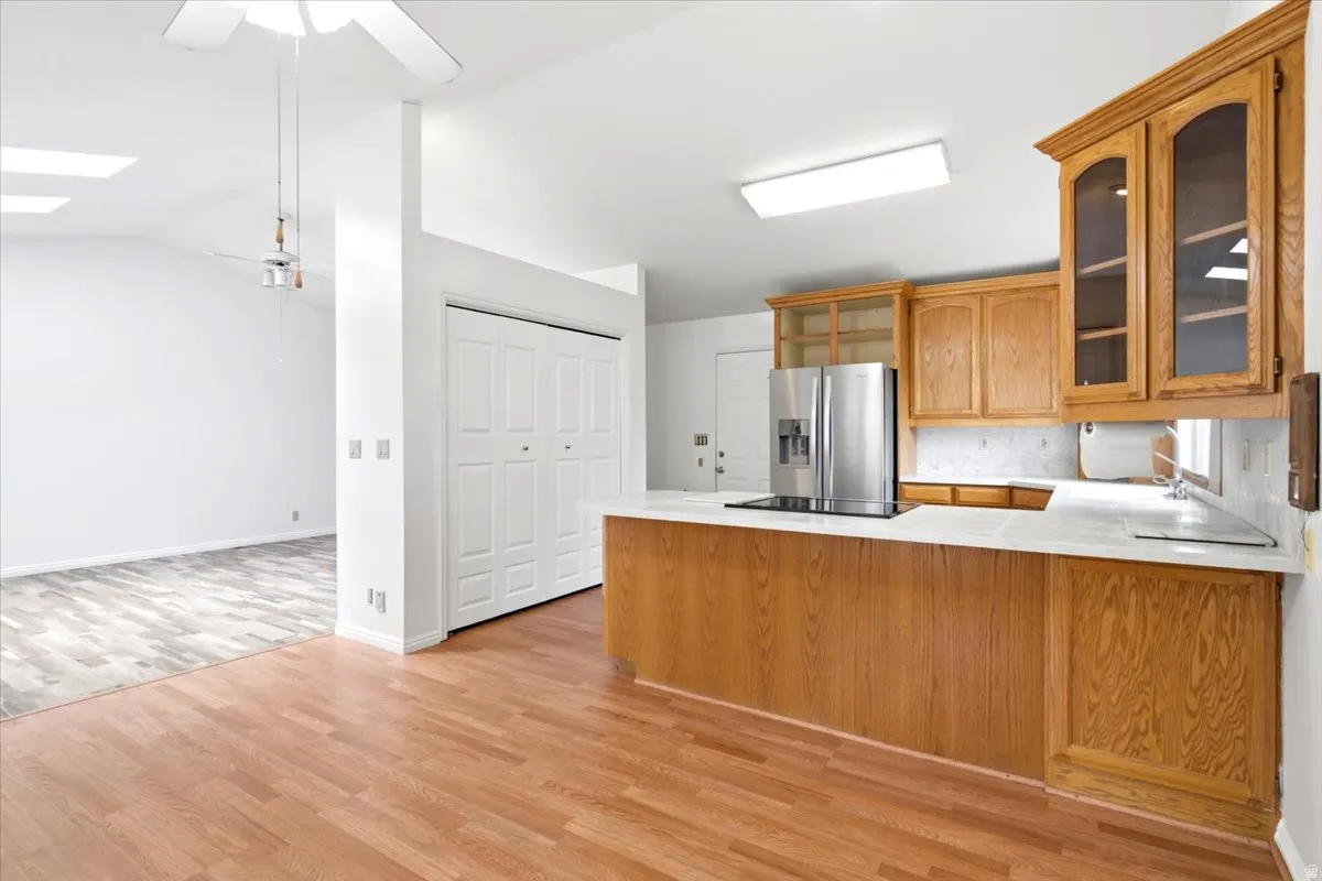 Kitchen features wood-finish cabinetry, a stainless steel refrigerator, and a white tile countertop with a matching backsplash