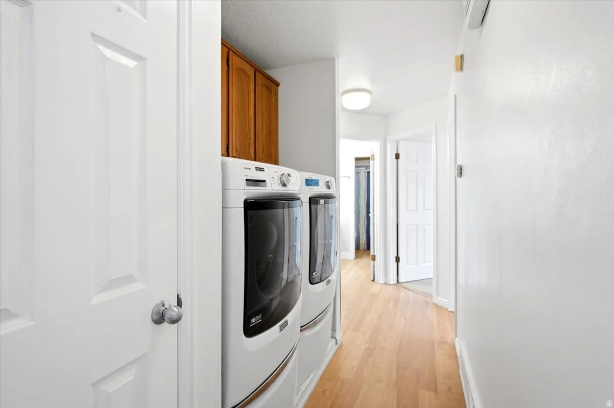 Dedicated laundry area featuring wood-finish flooring and upper wood cabinetry