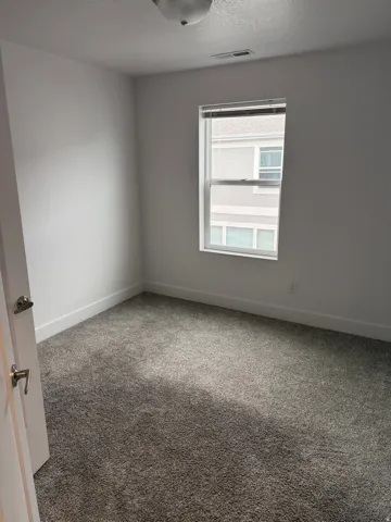 Neutral-toned room featuring plush grey carpeting and white baseboards