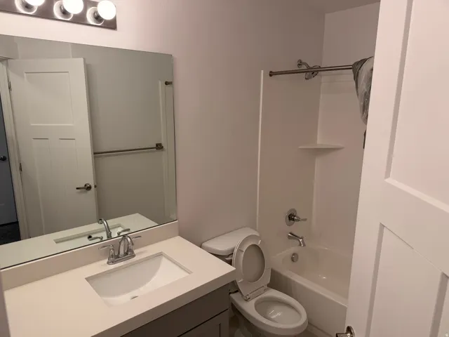 Bathroom featuring a single vanity with an integrated sink, polished chrome faucet, and a large wall-mounted mirror