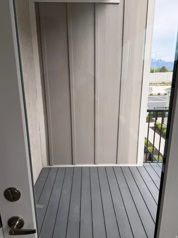 Private balcony featuring gray composite decking, board and batten siding, and a black metal railing