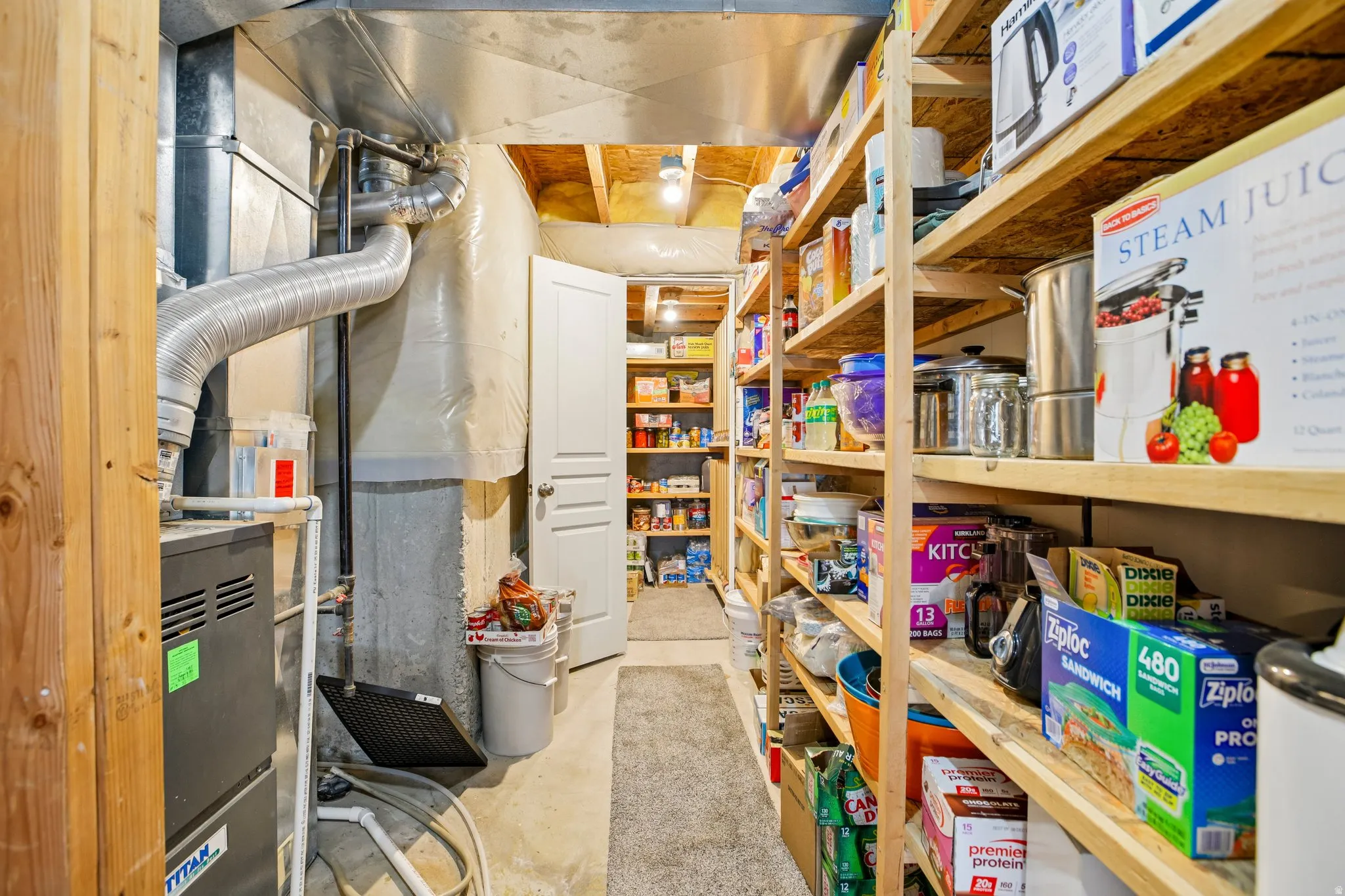 Extensive basement storage area featuring built-in wood shelving, exposed ductwork, and a utility door