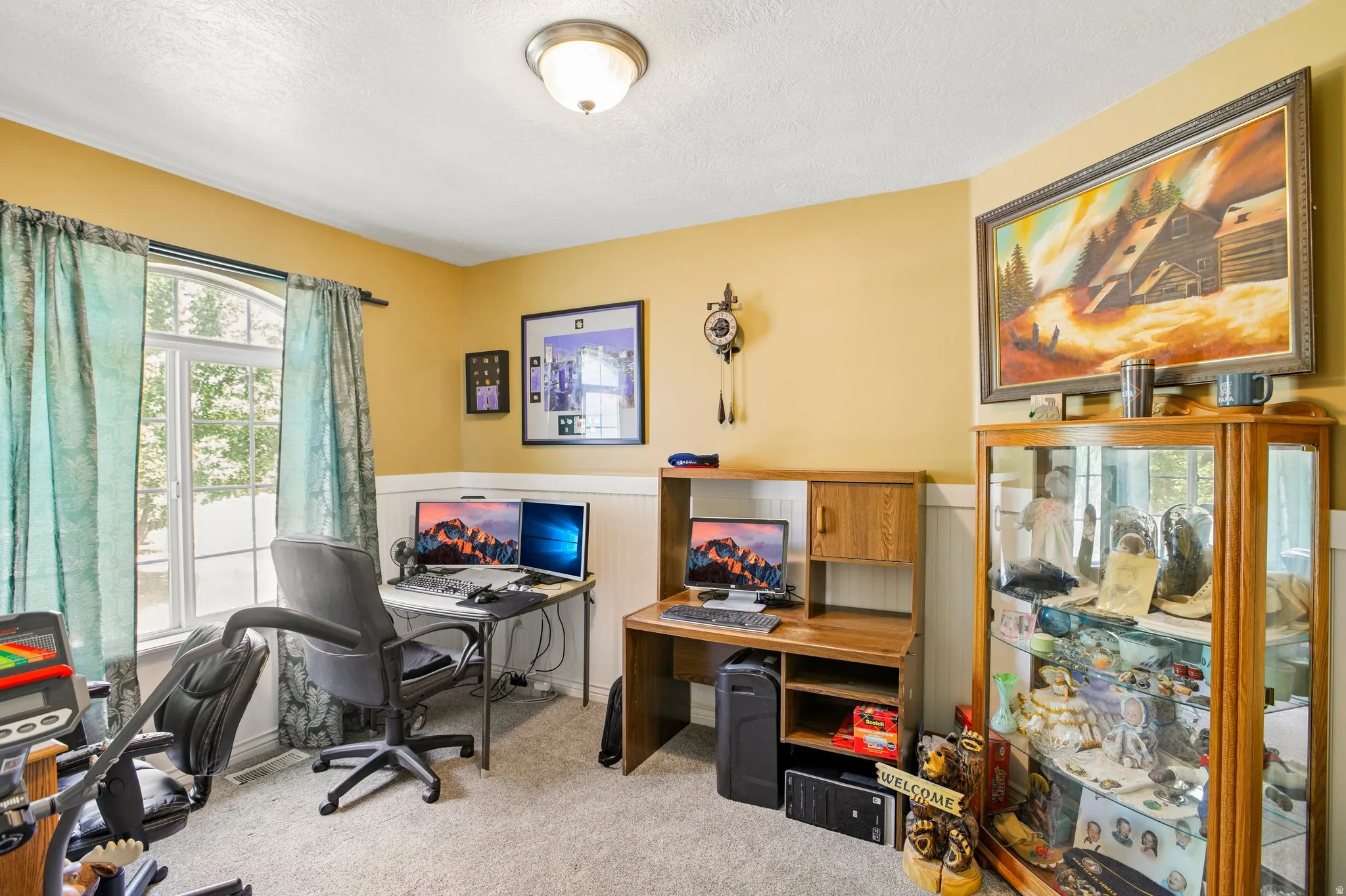 Versatile interior space featuring light-colored walls with wainscoting, an arched window, and a built-in wood-finish desk