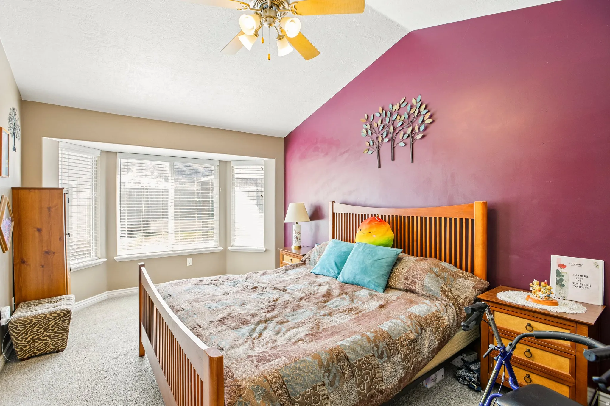 Vaulted ceiling with a ceiling fan light fixture, bay window with blinds, and neutral carpet flooring