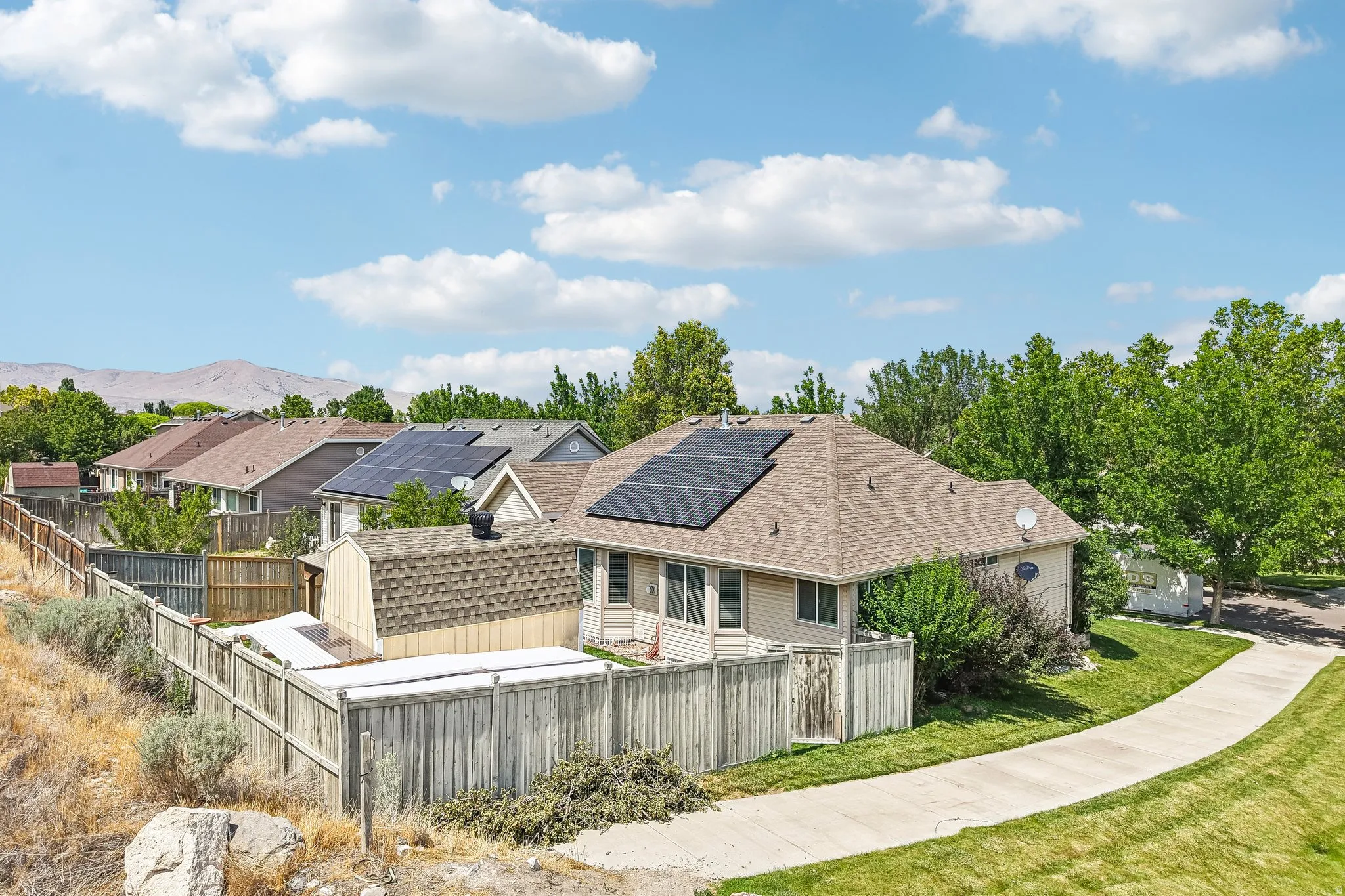 Property featuring a light tan exterior, a brown shingle roof, and multiple solar panels