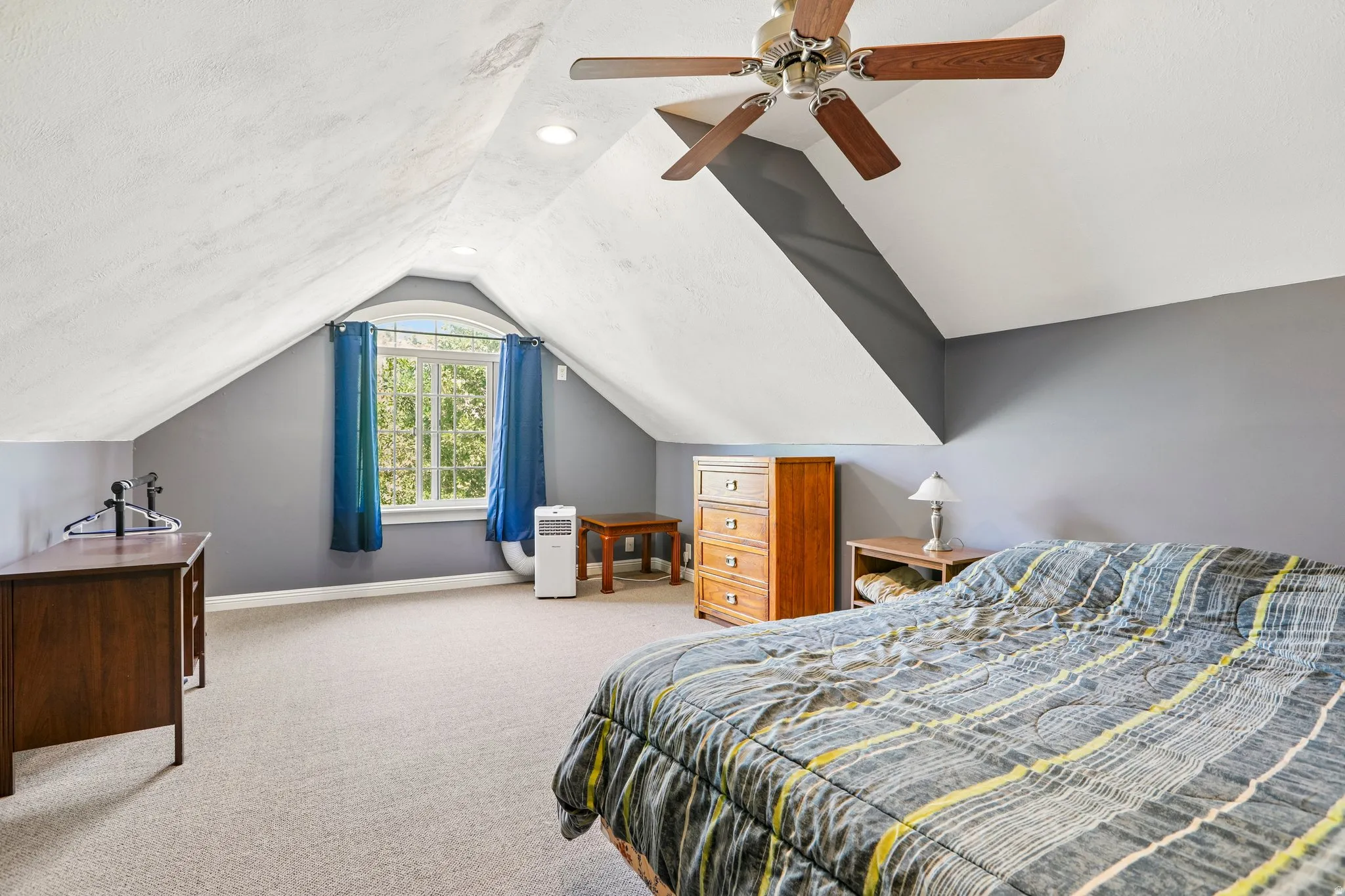 Spacious room featuring sloped ceilings, recessed lighting, and a ceiling fan
