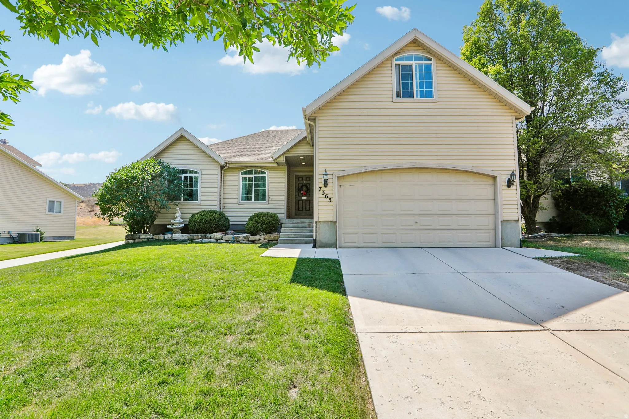 Two-story residence featuring light-colored siding, an attached garage, and a concrete driveway