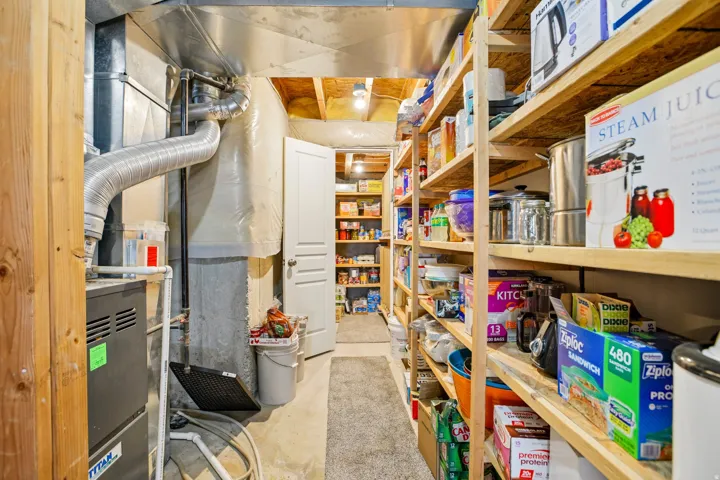 Extensive basement storage area featuring built-in wood shelving, exposed ductwork, and a utility door