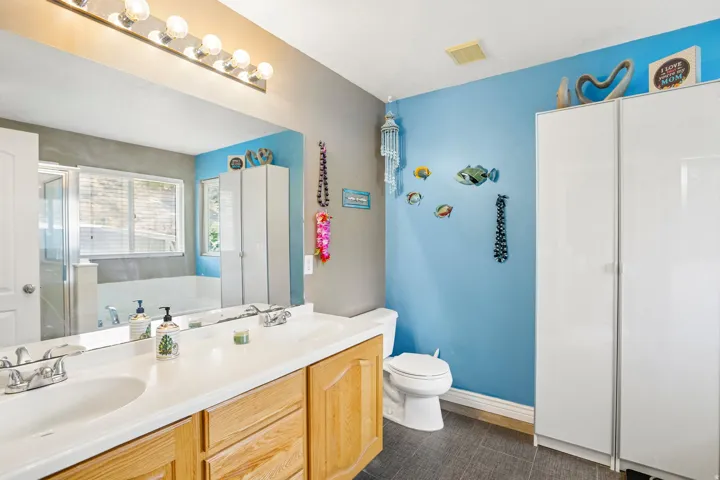 Dual vanity with integrated sinks, light wood-finish cabinetry, and a large mirror