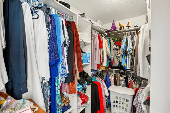 Walk-in closet featuring white wall shelving and multiple clothing rods