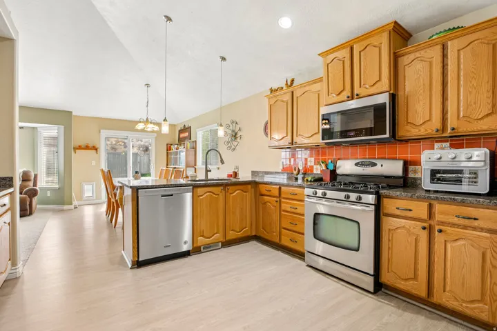 Kitchen with wood cabinetry, granite-style countertops, and a full suite of stainless steel appliances