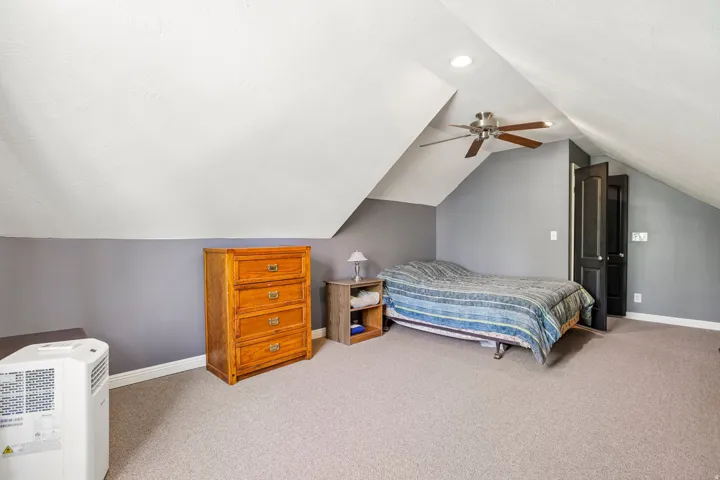 Carpeted room featuring a sloped ceiling, recessed lighting, and a ceiling fan with wood-finish blades