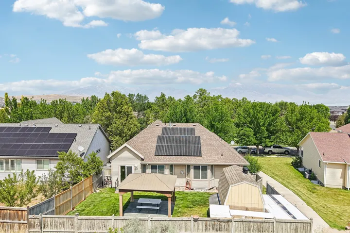 Rear exterior featuring a covered patio, fenced yard, and solar panels