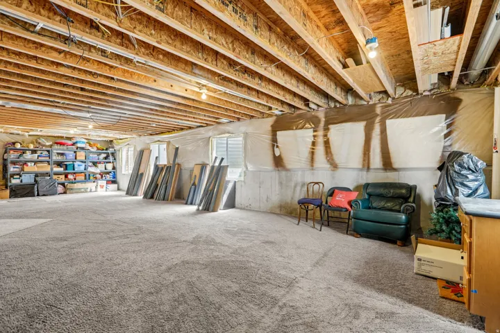 Spacious unfinished basement featuring exposed wood joists and concrete walls