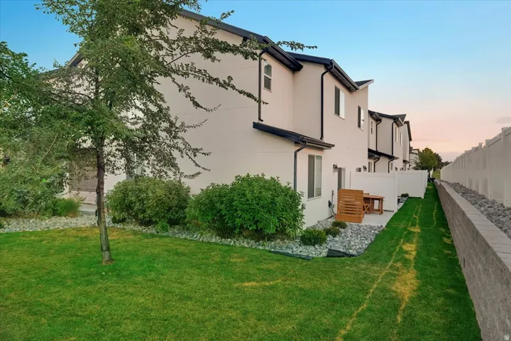Rear exterior featuring a patio, manicured lawn, and privacy fencing