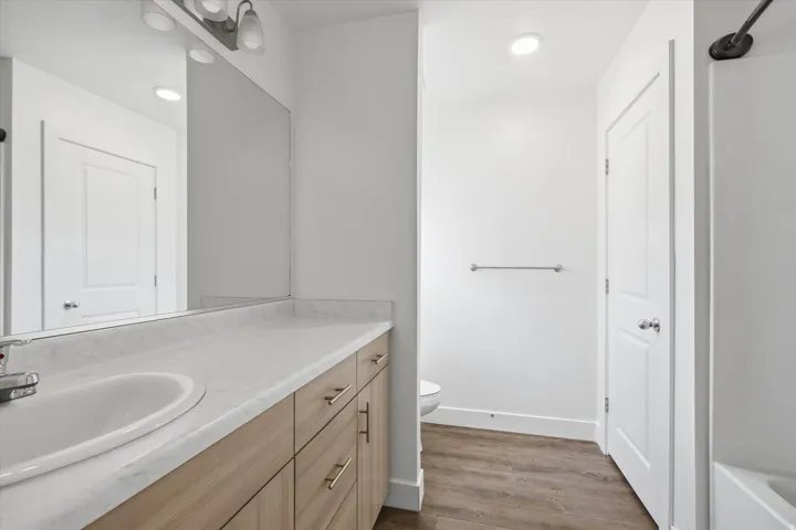 Bathroom vanity featuring wood-finish cabinetry, a white countertop, and an integrated white sink with chrome faucet