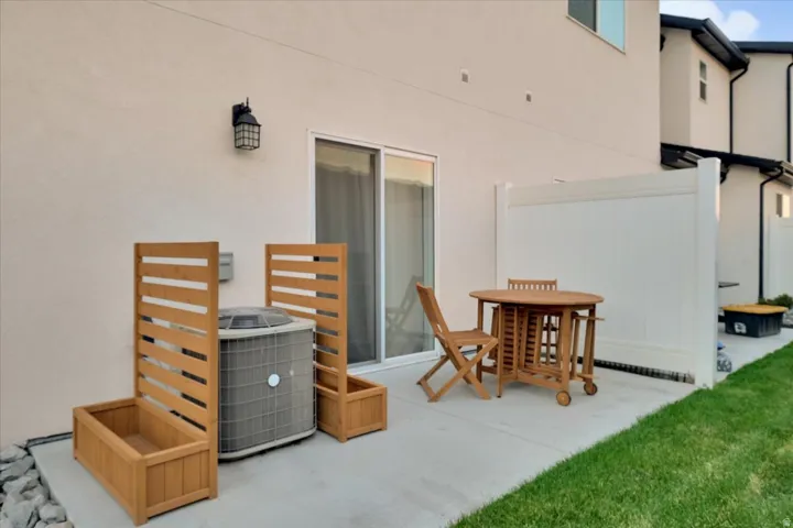 Private rear patio space featuring a concrete pad, a white vinyl privacy fence, and a sliding glass door