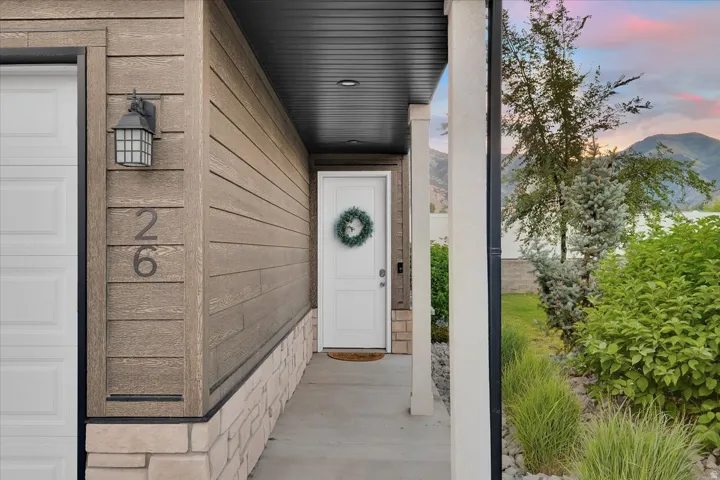 Inviting entryway featuring natural-toned horizontal siding with stone veneer accents