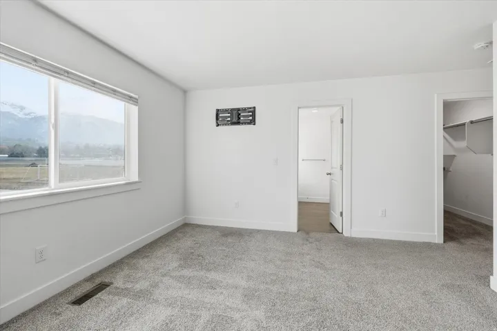 Carpeted room with a large window, offering a scenic mountain and field backdrop