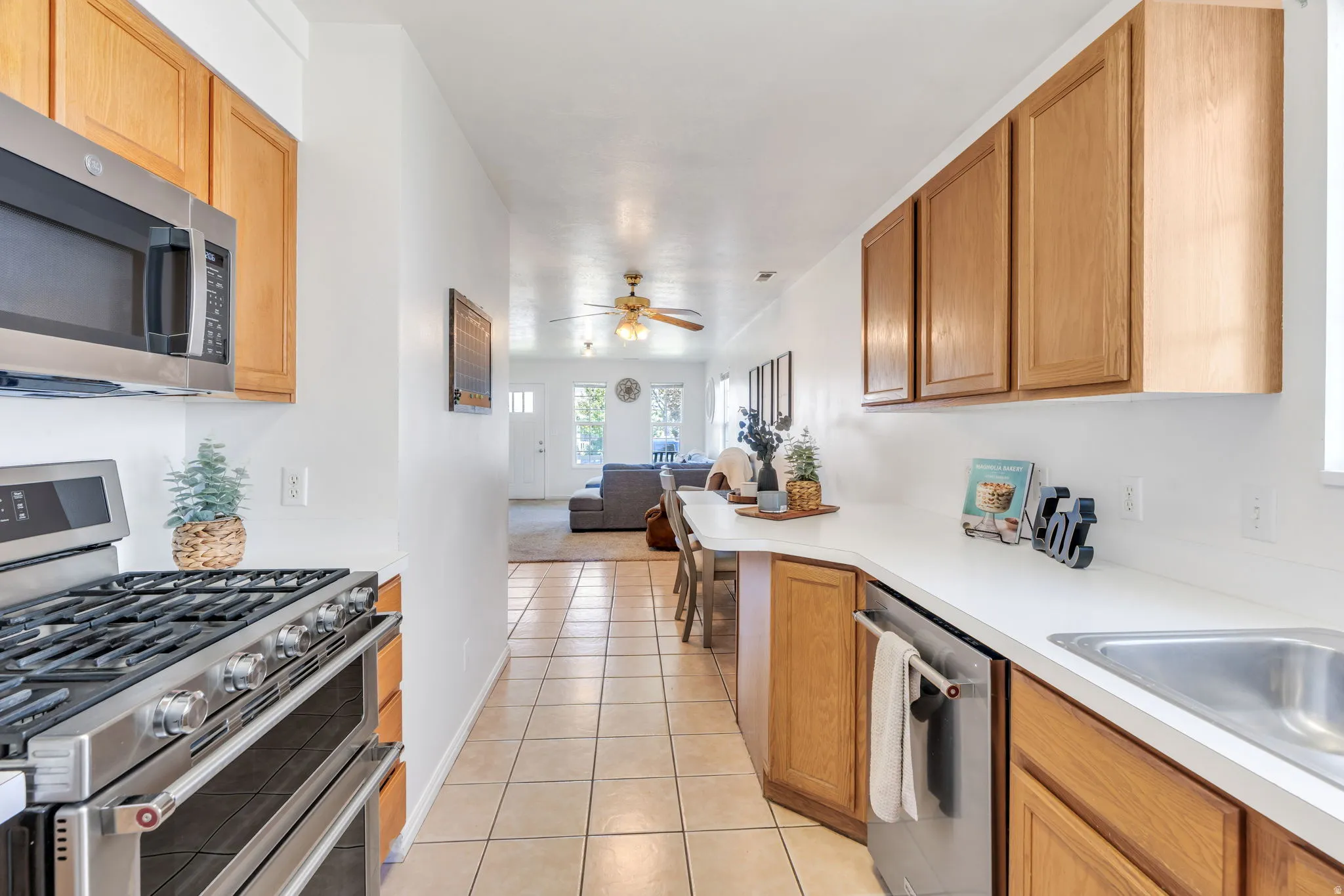 Kitchen featuring light wood-finish cabinetry, stainless steel appliances, a gas range with a double oven, and a built-in microwave