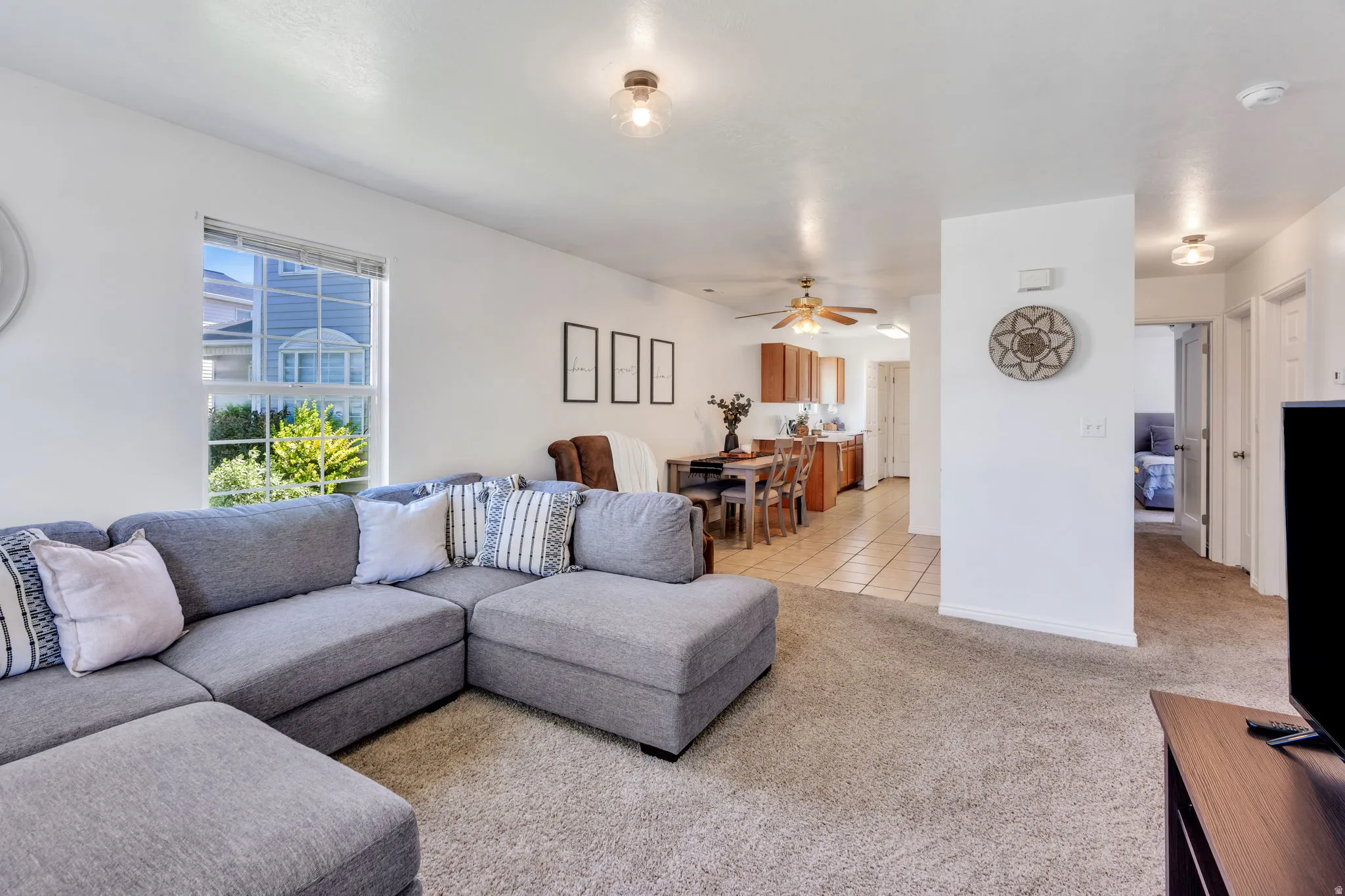 Open-concept living space featuring neutral carpeting, white walls, and a large window providing natural light