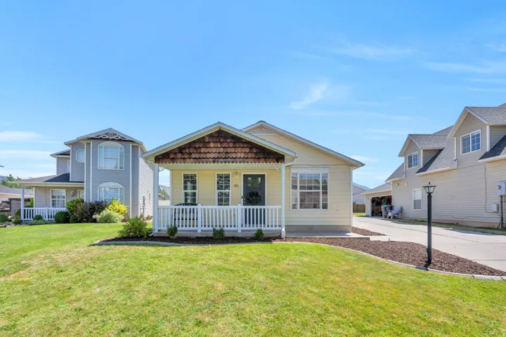 Single-story home featuring light yellow siding and a covered front porch with white railing