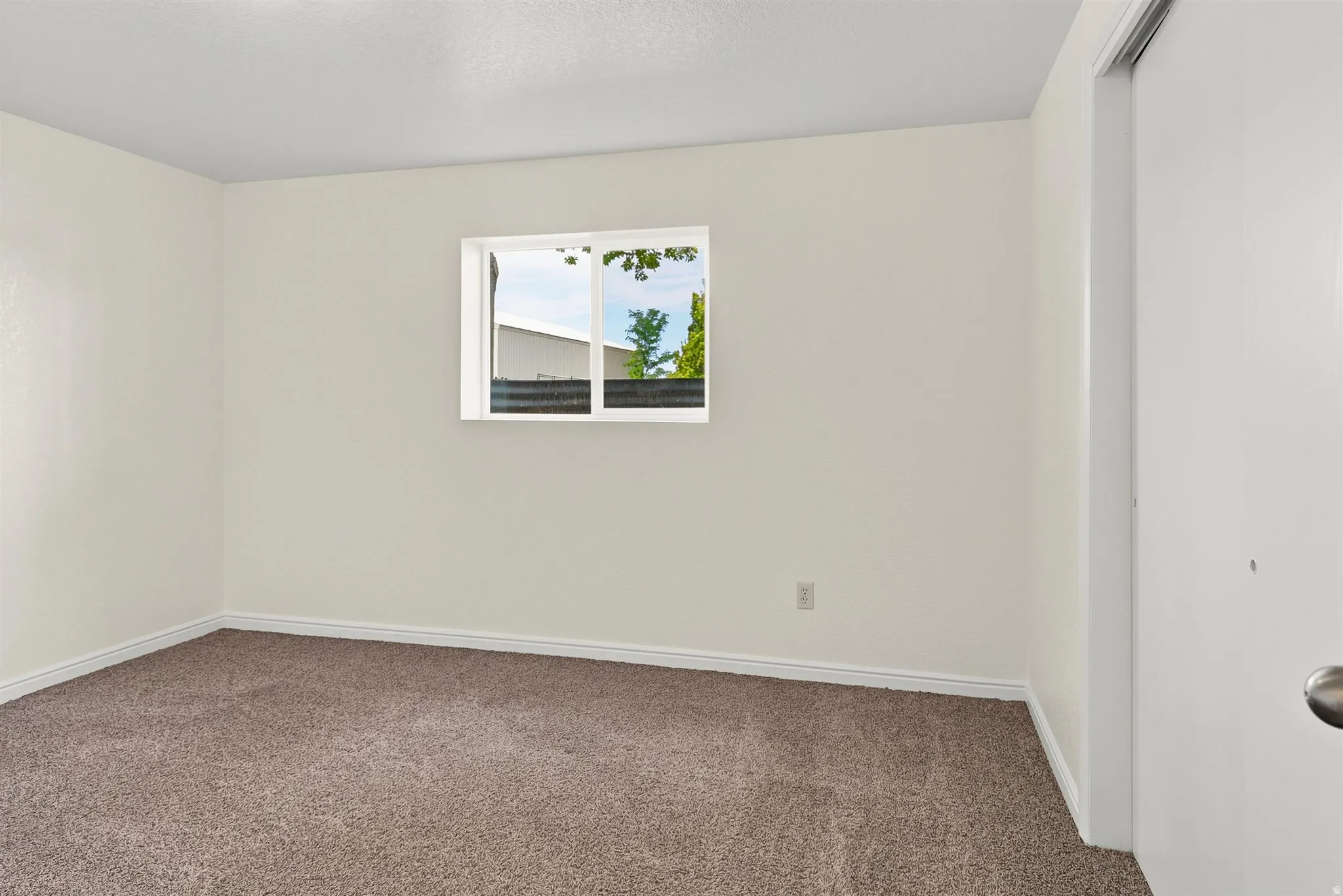 Room featuring light beige wall paint, brown carpeting, and white trim