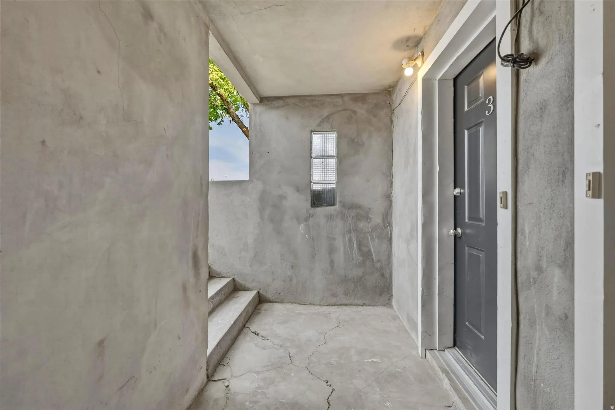 Entryway featuring a paneled door with a numeric plaque, concrete flooring, and a small rectangular window