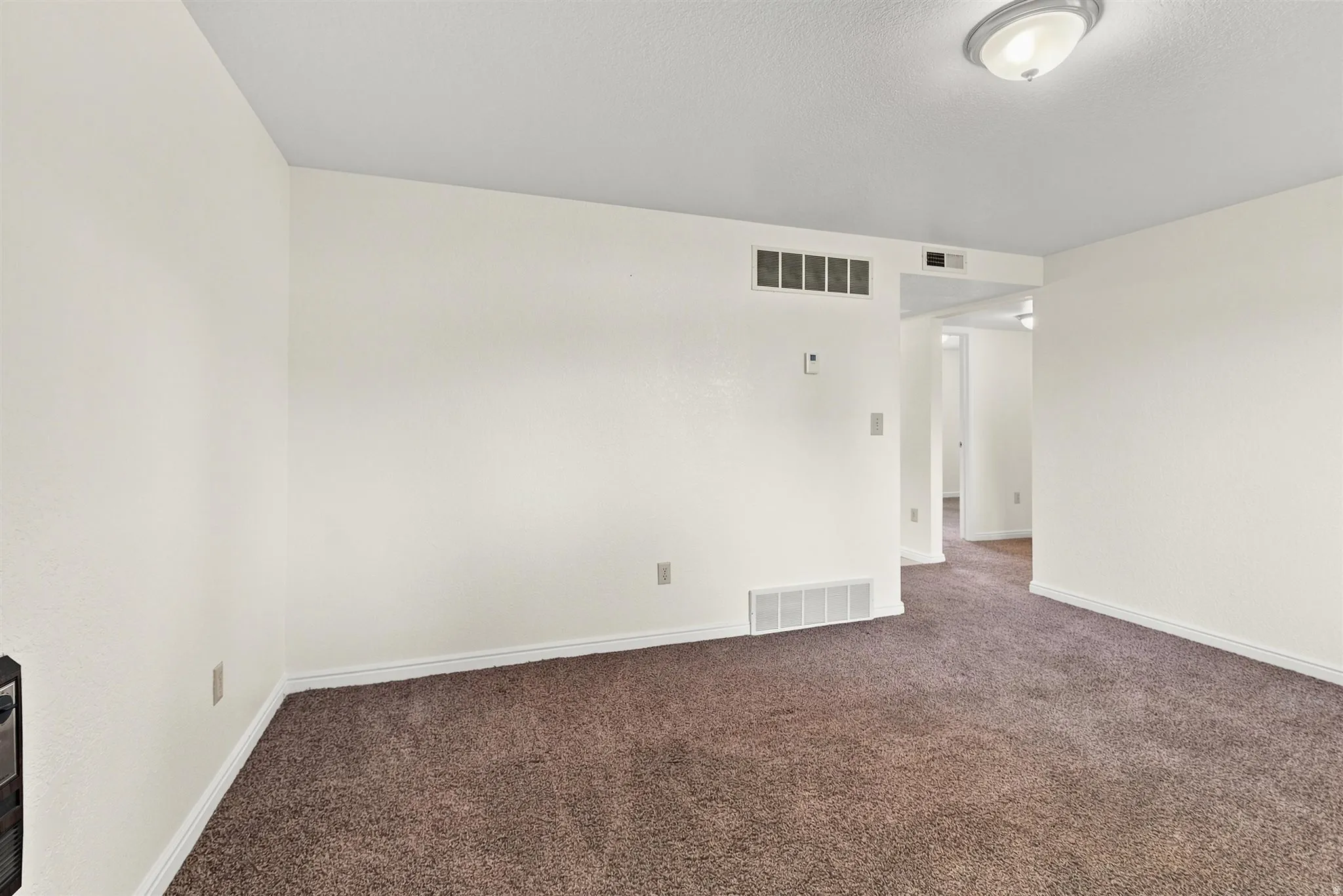 Spacious room with plush brown carpet, white walls, and white trim