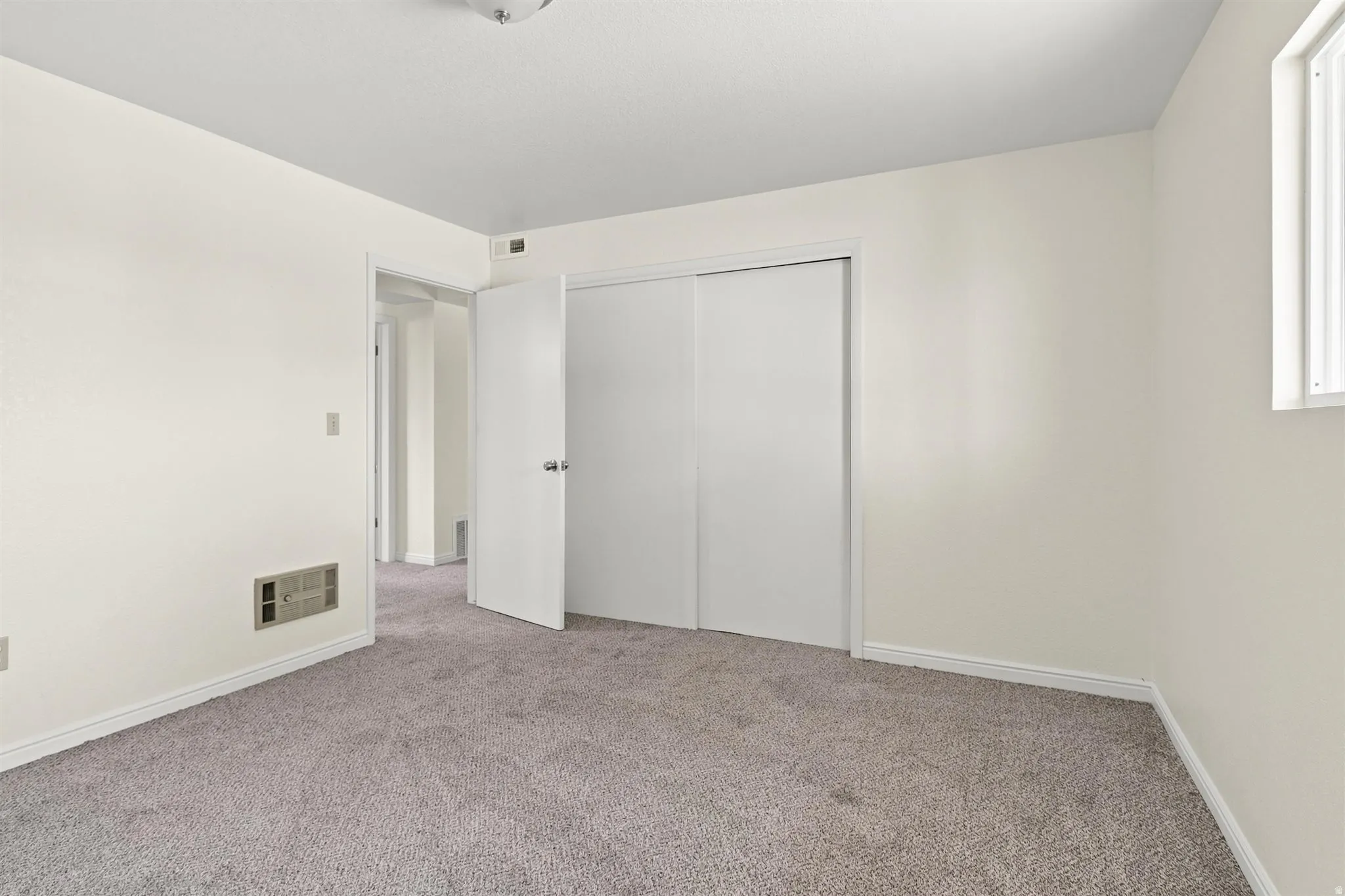Carpeted room featuring a double-door closet, a single window, and neutral wall tones