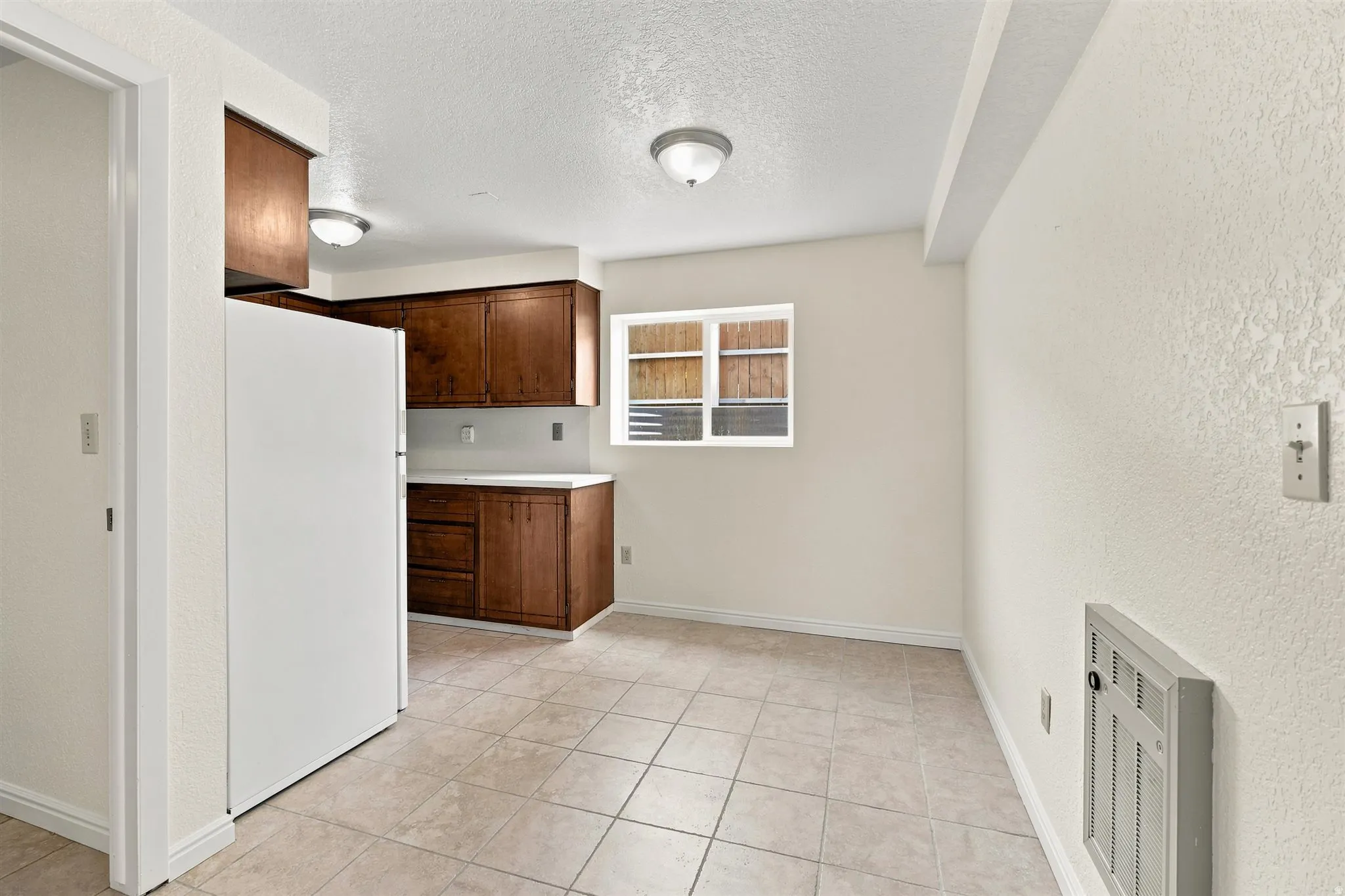 Kitchen area featuring wood-finish cabinetry, light countertops, and a tile floor