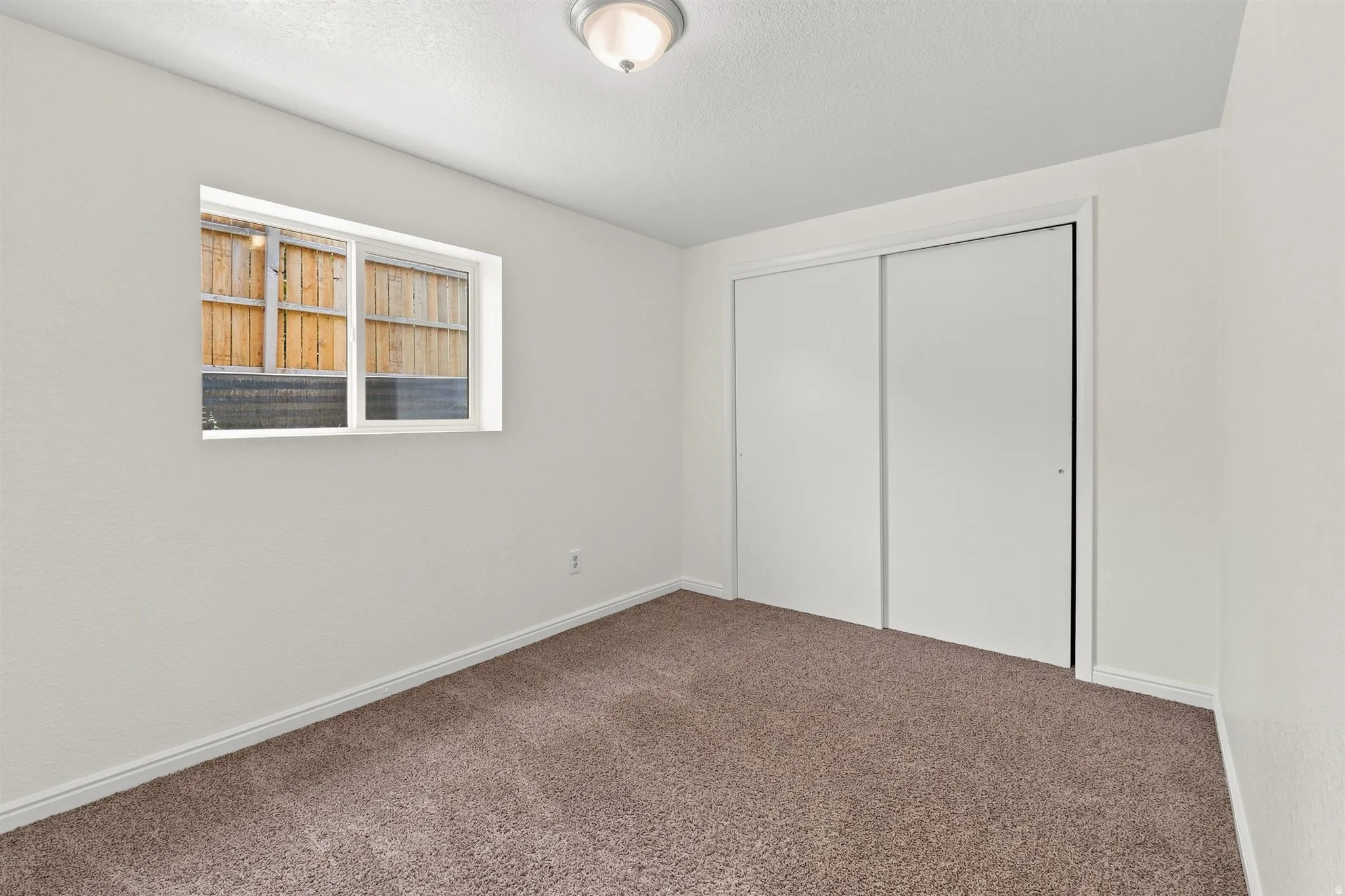 Room featuring neutral-toned walls, brown carpet flooring, and a white baseboard trim
