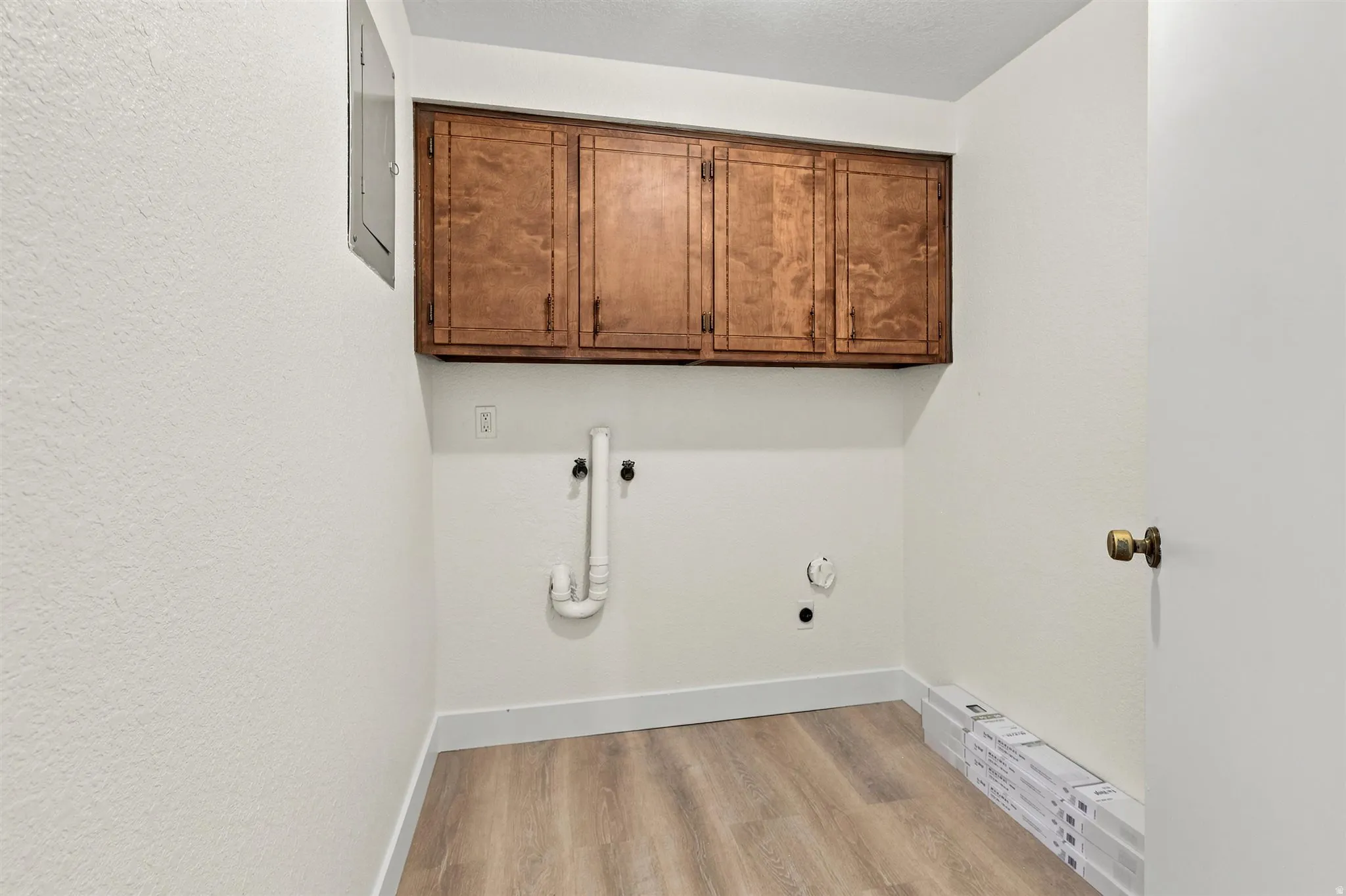 Laundry area featuring wood-finish flooring, white walls, and built-in wood cabinetry