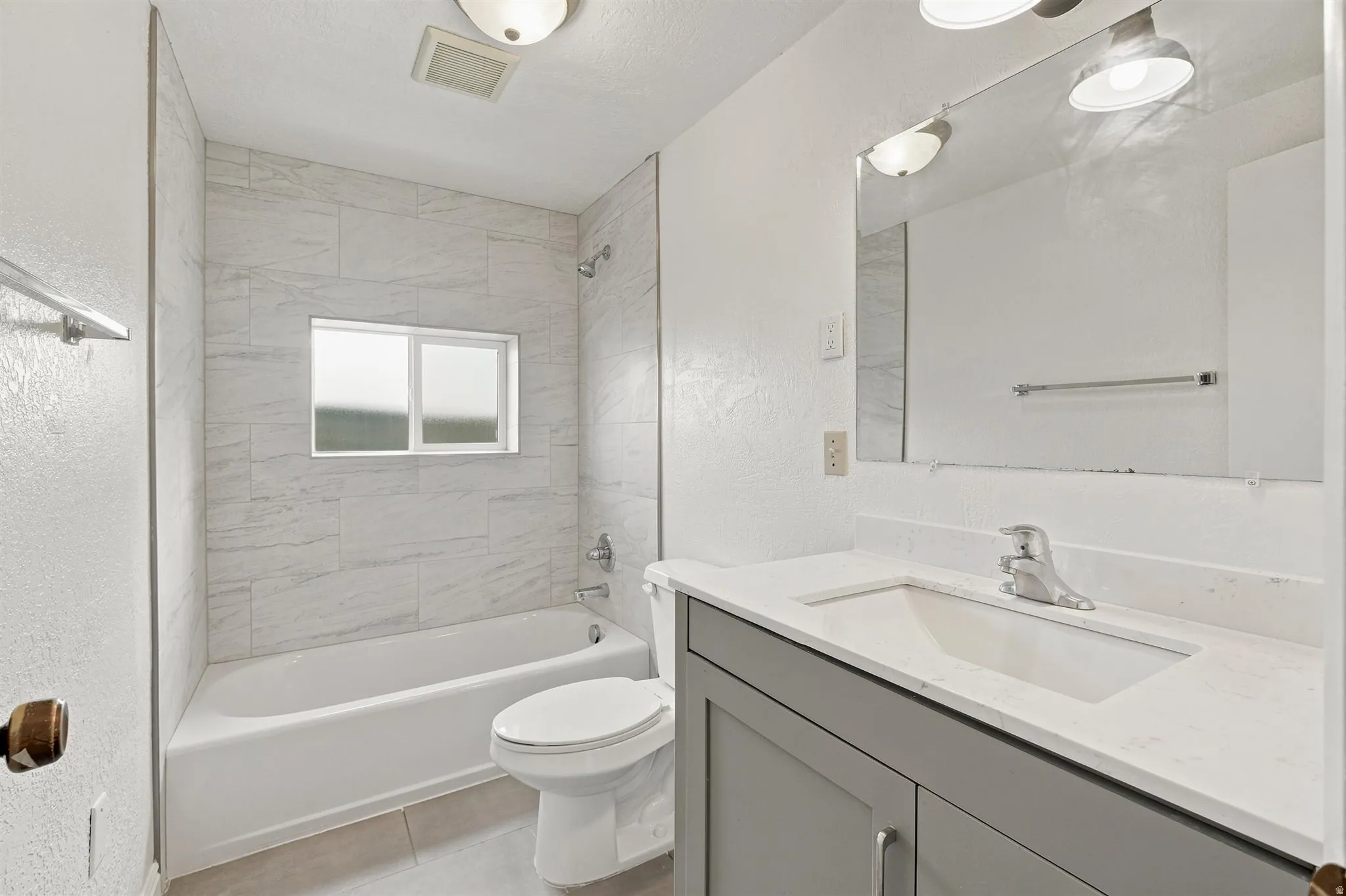 Bathroom featuring a white bathtub, tiled shower surround, and a window