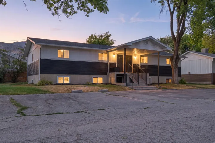 Multi-unit property with a covered porch entry, dual front doors, and an asphalt parking area